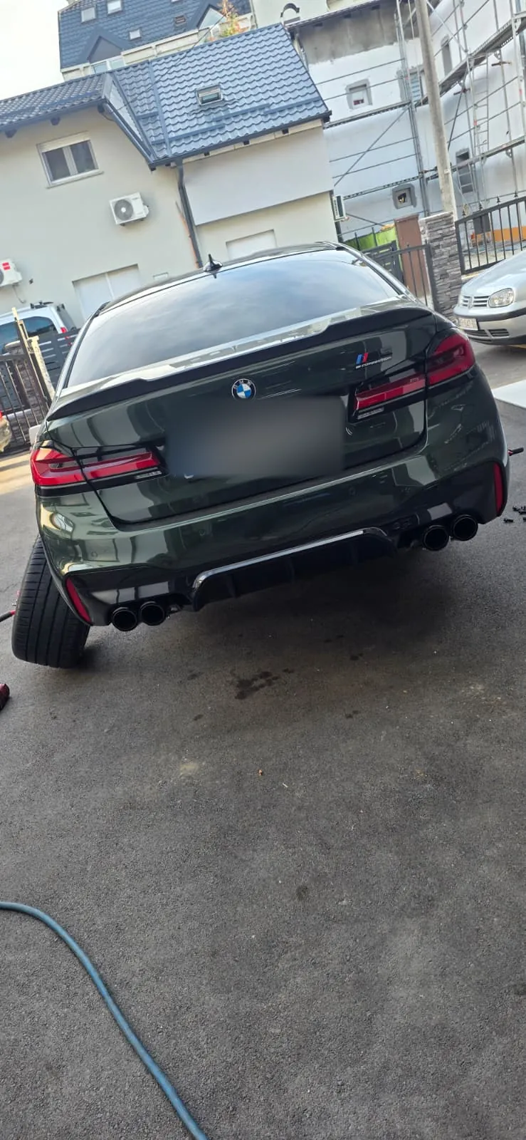 Tamnozeleni BMW serije M sa skinutim kotačem ispred radionice