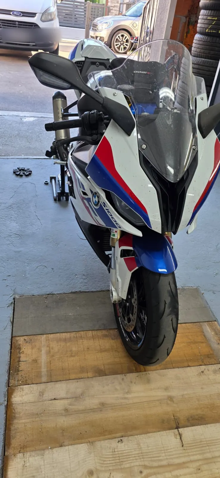 Motocikl BMW S 1000 RR u bojama BMW M na drvenoj podlozi ispred radionice